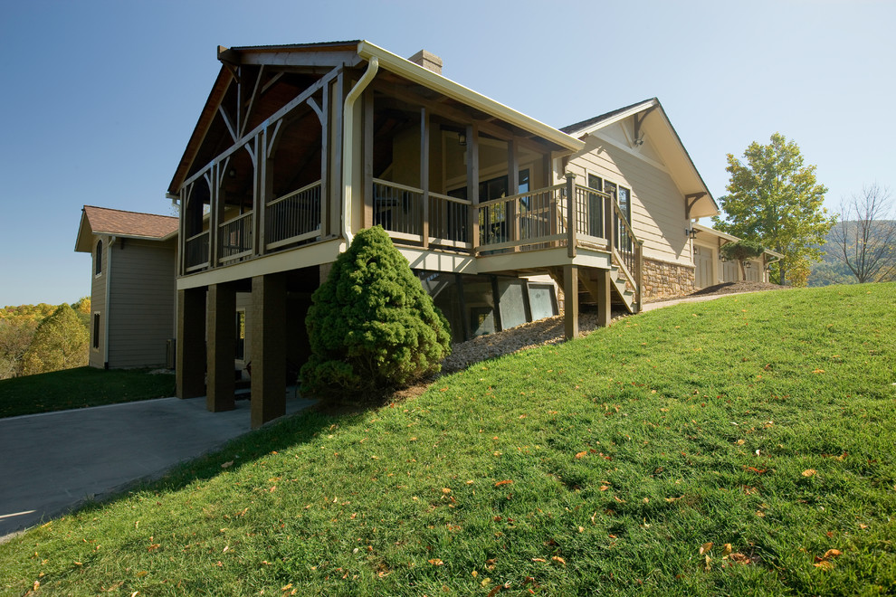Diseño de fachada beige de estilo americano grande a niveles con revestimiento de aglomerado de cemento y tejado a dos aguas