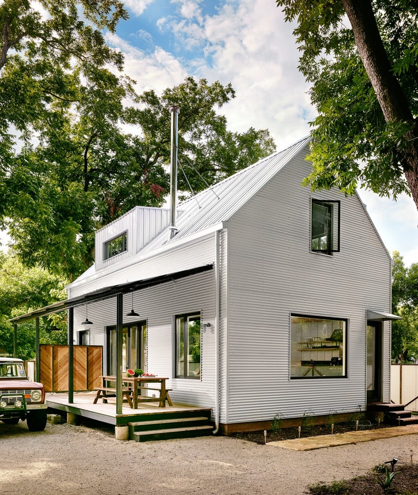 Immagine della facciata di una casa bianca country a due piani con rivestimento in metallo e tetto a capanna