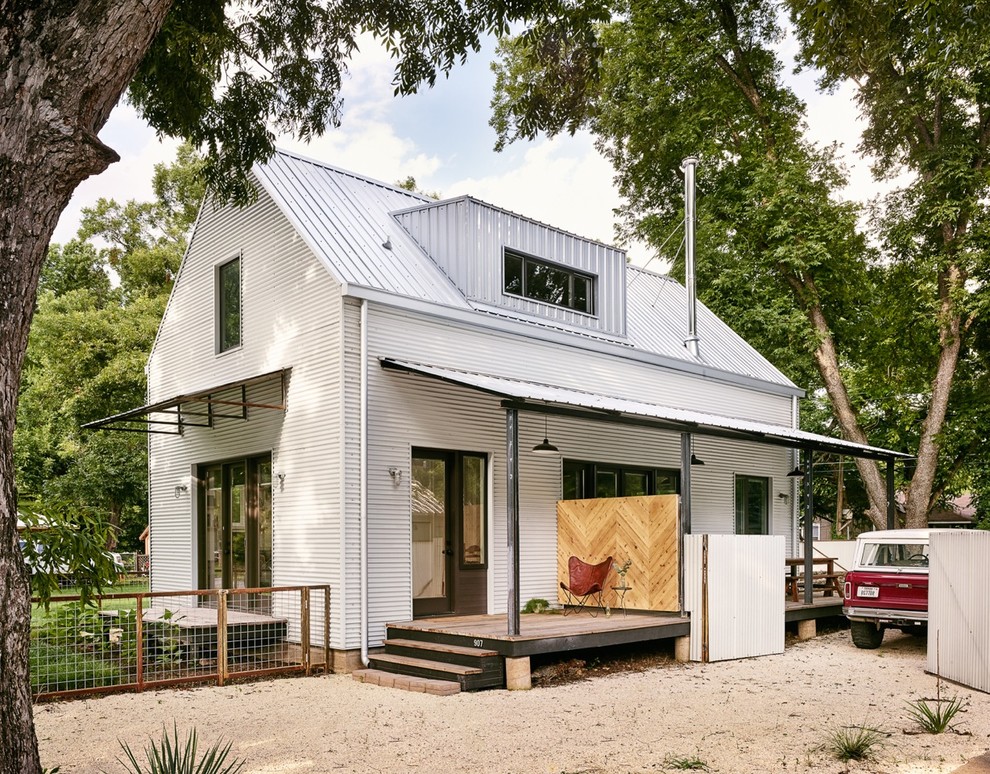 На фото: маленький, двухэтажный, белый дом в стиле кантри с облицовкой из металла и двускатной крышей для на участке и в саду с