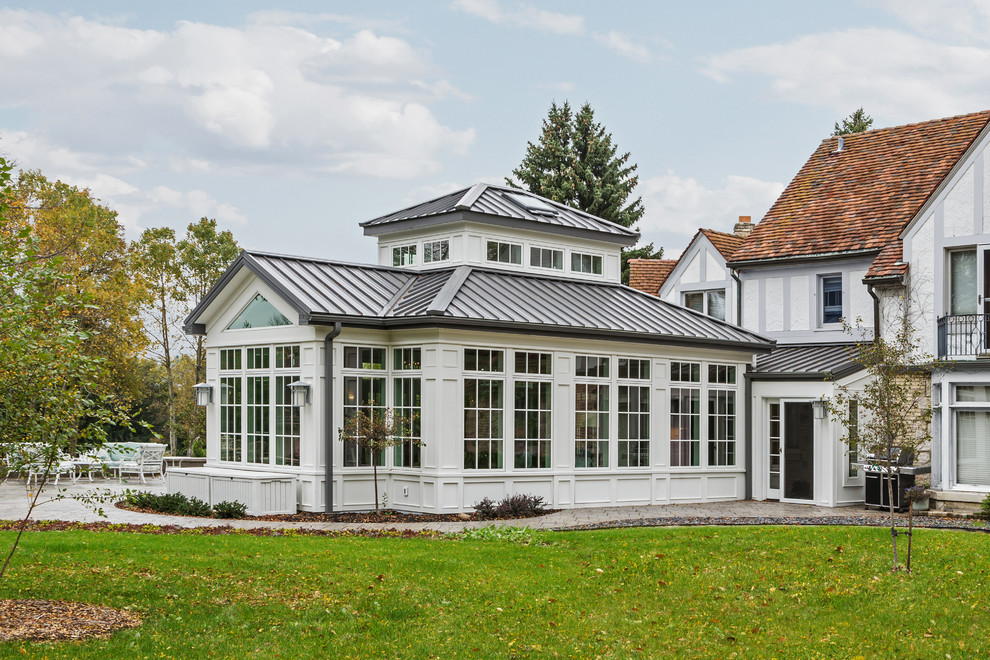 Esempio della villa grande bianca classica a un piano con rivestimento in legno, tetto a padiglione e copertura in metallo o lamiera