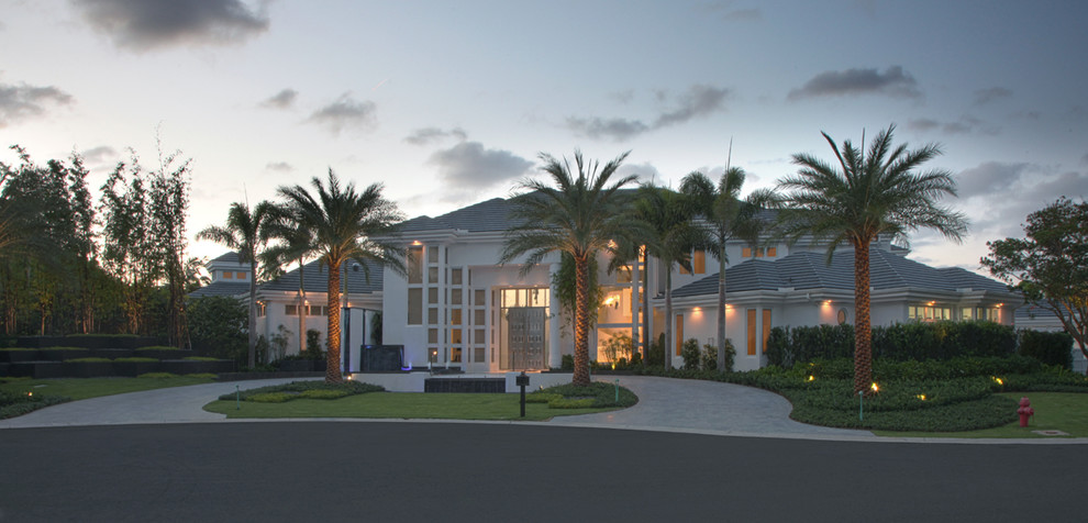 Пример оригинального дизайна: огромный, двухэтажный, белый дом в стиле модернизм с облицовкой из цементной штукатурки и вальмовой крышей