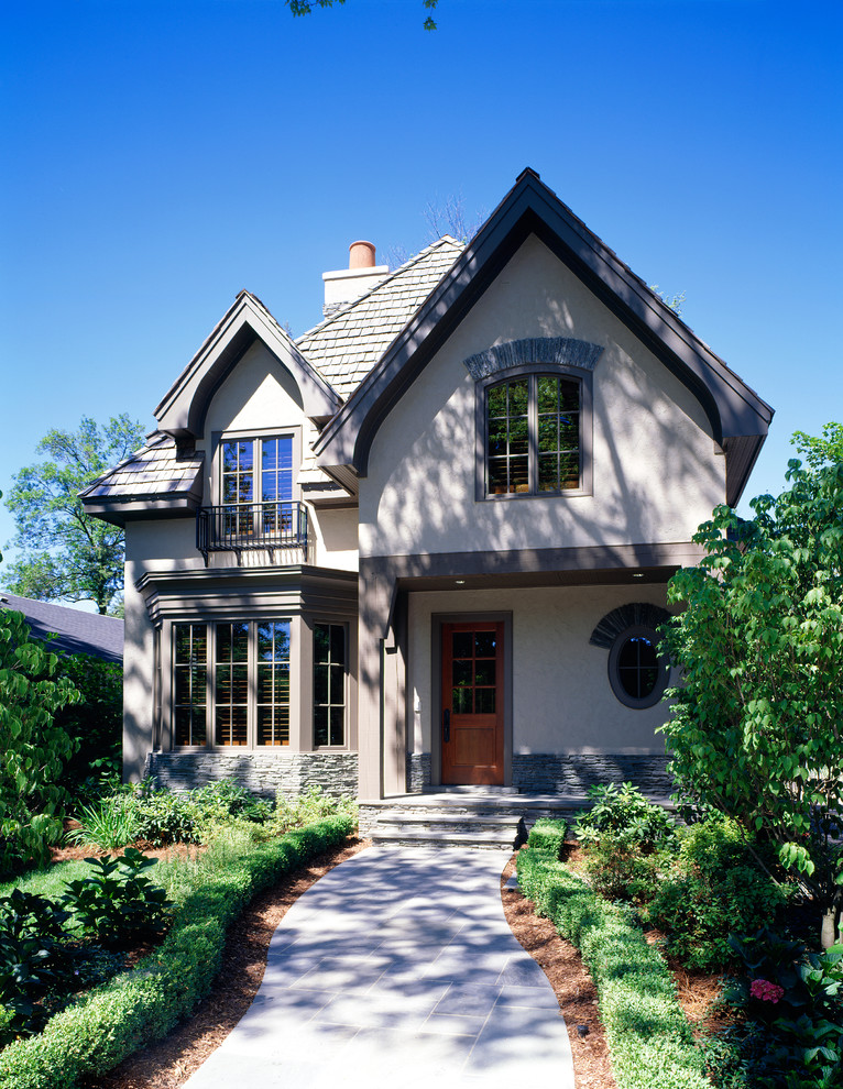 Diseño de fachada de casa beige tradicional renovada de tamaño medio de dos plantas con revestimiento de estuco, tejado a dos aguas y tejado de teja de madera