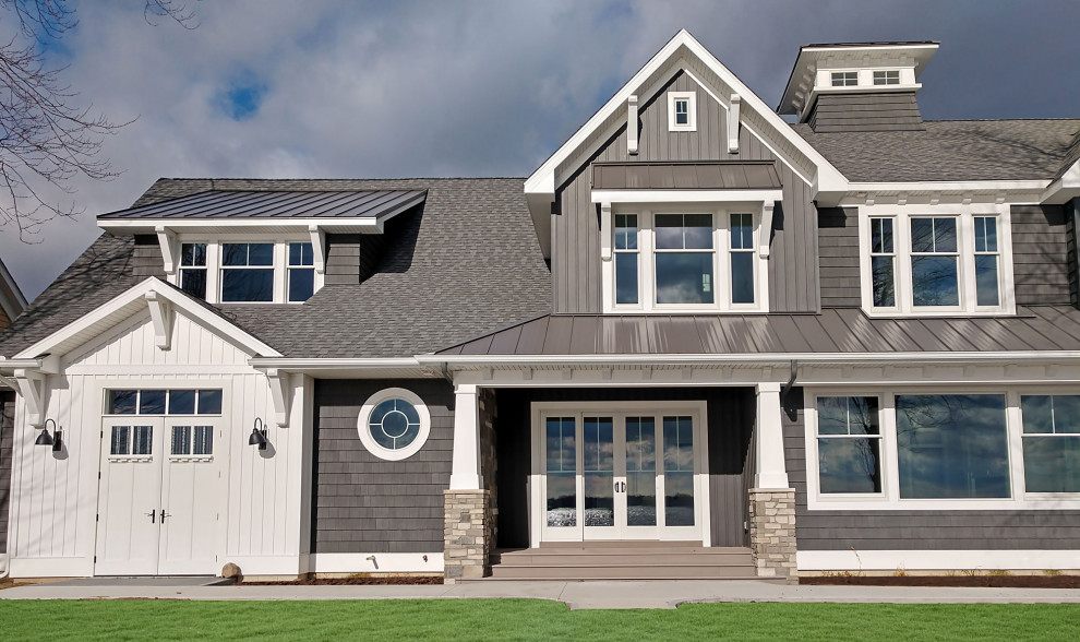 Cette photo montre une façade de maison grise craftsman à un étage avec un revêtement en vinyle, un toit à deux pans et un toit mixte.