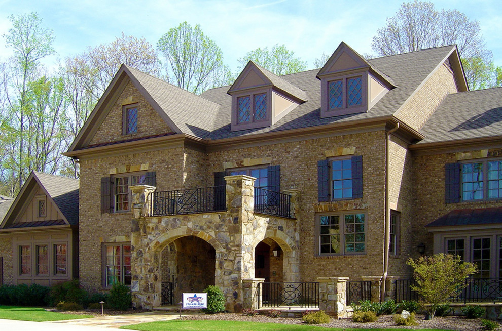 Foto della villa marrone american style a tre piani con rivestimento in pietra, tetto a capanna e copertura a scandole