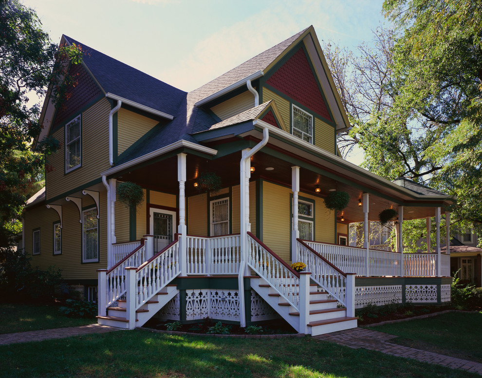 Diseño de fachada de casa amarilla y azul tradicional grande de dos plantas con tejado a dos aguas, tejado de teja de madera, revestimiento de vinilo y tablilla
