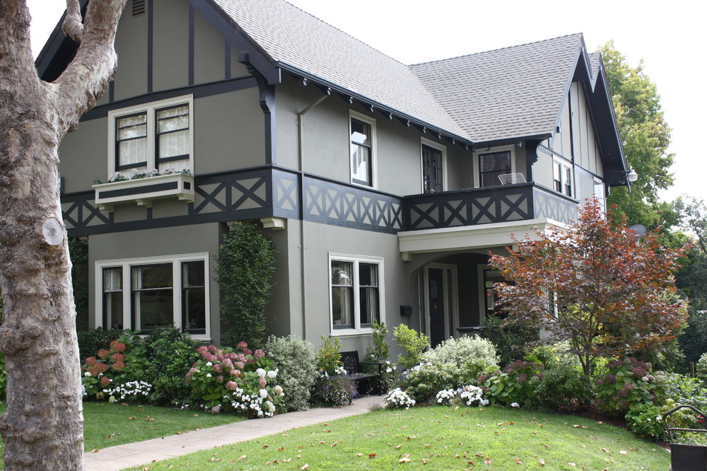 Esempio della villa grande grigia american style a due piani con rivestimento in stucco e copertura in tegole