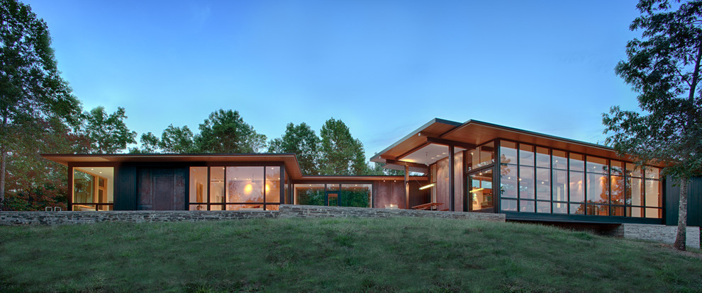 На фото: коричневый частный загородный дом в современном стиле с комбинированной облицовкой и односкатной крышей