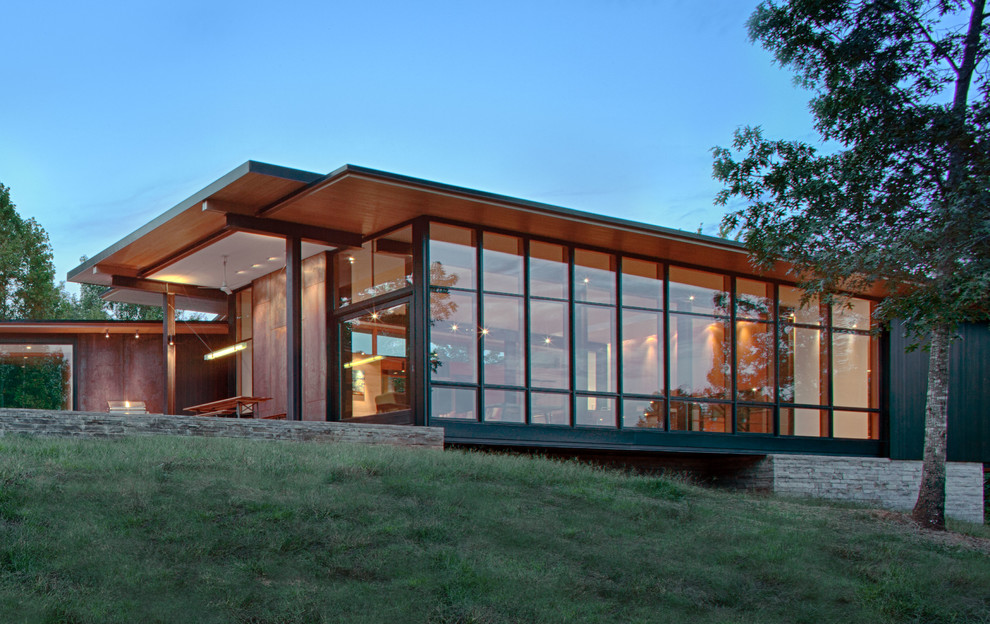 На фото: коричневый частный загородный дом в стиле модернизм с комбинированной облицовкой и односкатной крышей