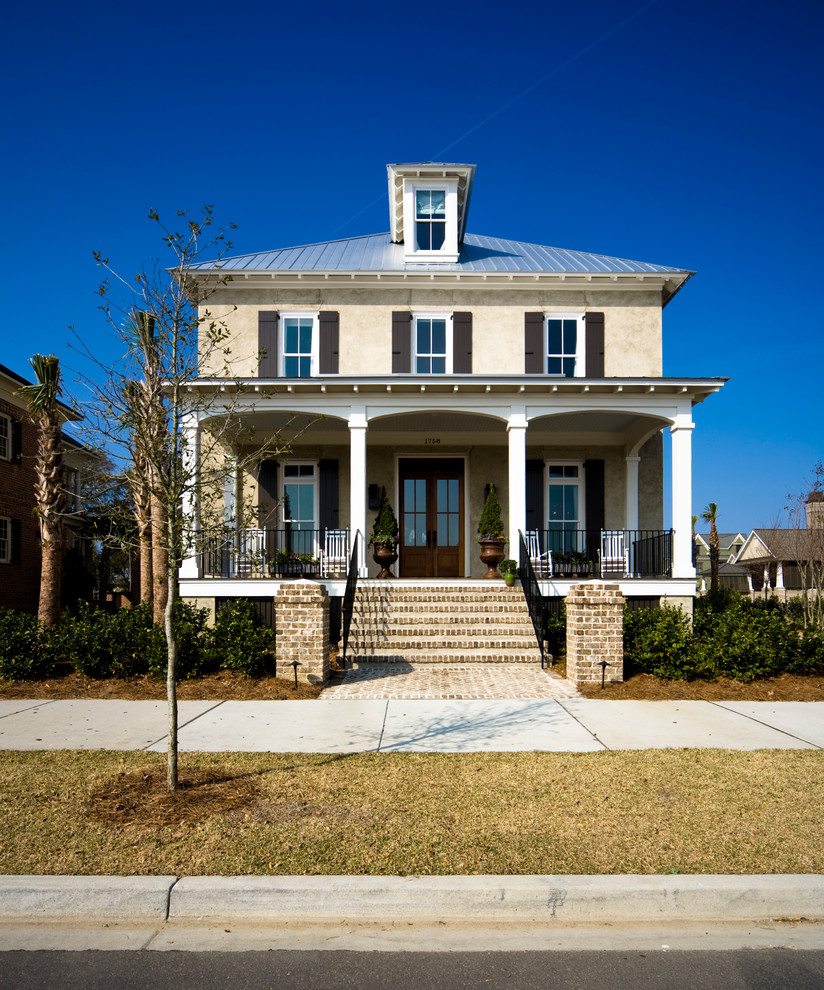 Exemple d'une façade de maison beige chic en stuc de taille moyenne et à un étage avec un toit à deux pans.