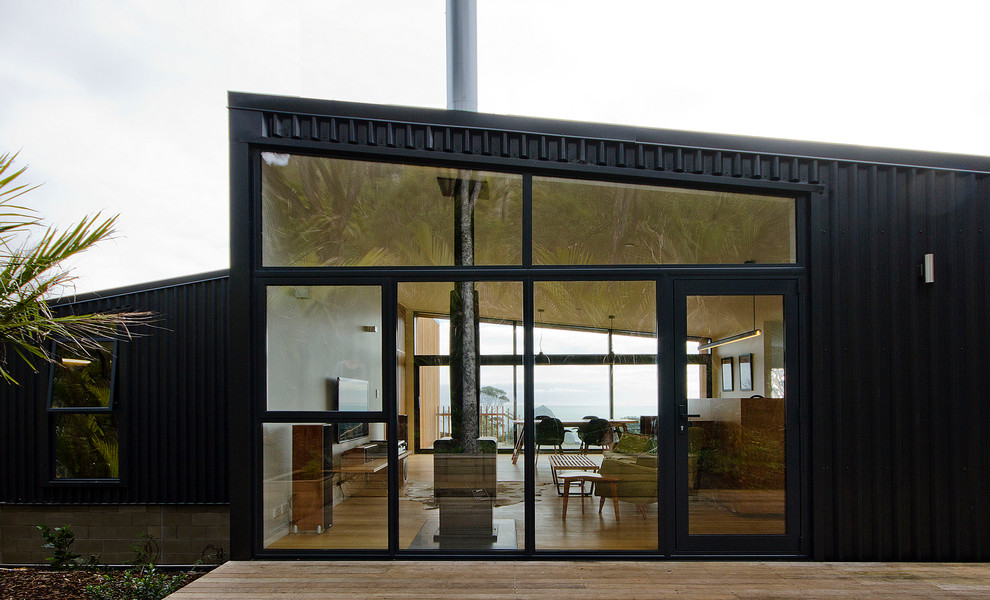 Immagine della facciata di una casa piccola nera stile marinaro a un piano con rivestimento in metallo e copertura in metallo o lamiera