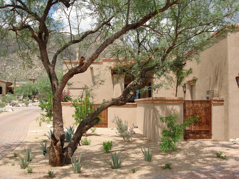 Cette image montre une grande façade de maison beige sud-ouest américain en adobe de plain-pied avec un toit plat et un toit en tuile.