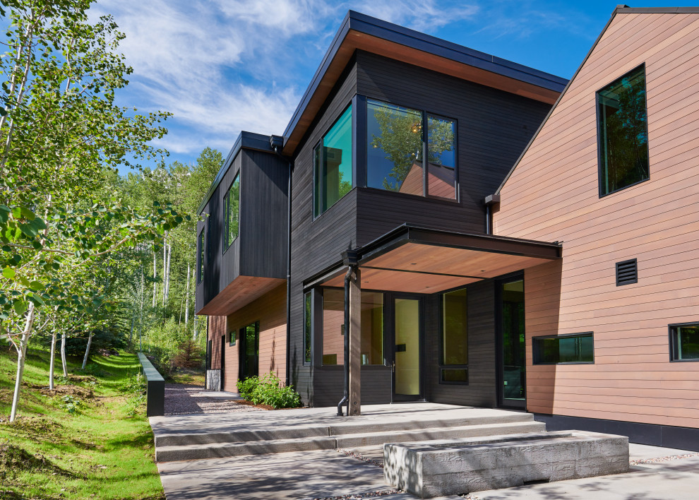 Réalisation d'une très grande façade de maison multicolore design en bois à deux étages et plus avec un toit en métal et un toit à quatre pans.