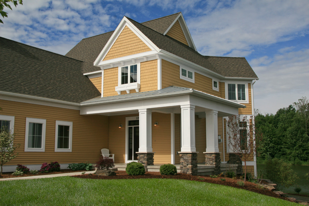 Idée de décoration pour une grande façade de maison jaune tradition en béton à deux étages et plus.