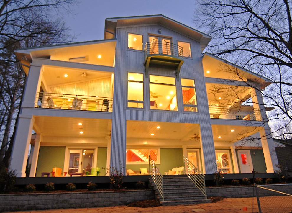 This is an example of a medium sized and white contemporary house exterior in Charlotte with three floors, metal cladding and a pitched roof.