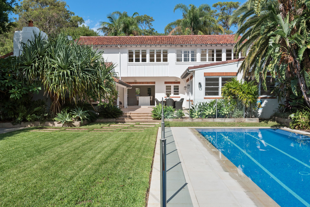 Expansive and white classic two floor concrete detached house in Sydney with a pitched roof and a tiled roof.