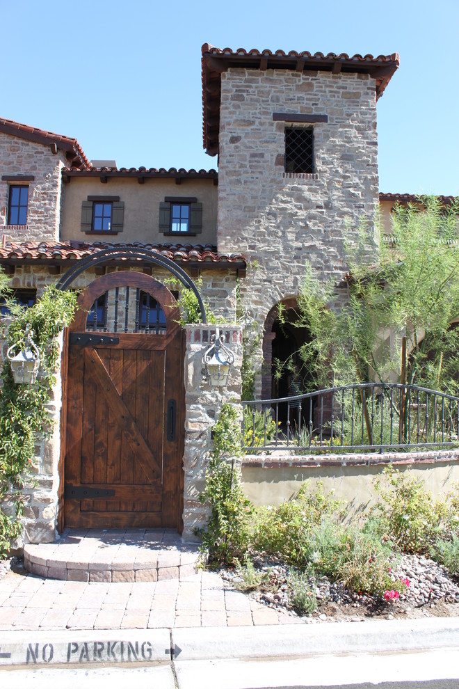 Idee per la villa grande grigia mediterranea a due piani con rivestimento in pietra, tetto a capanna e copertura in tegole