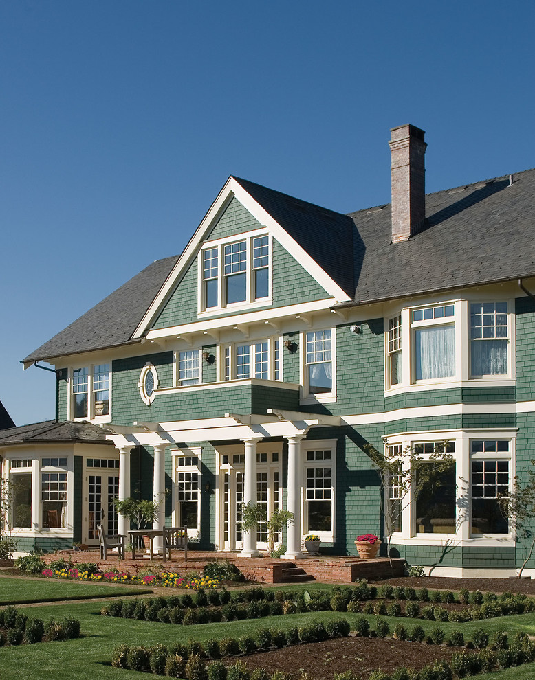 Immagine della facciata di una casa grande verde classica a tre piani con rivestimento in legno