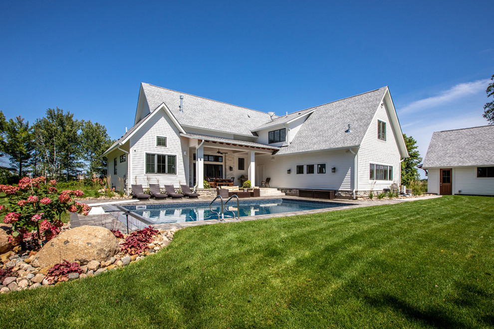 Mittelgroßes, Zweistöckiges Landhaus Einfamilienhaus mit Mix-Fassade, weißer Fassadenfarbe und Schindeldach
