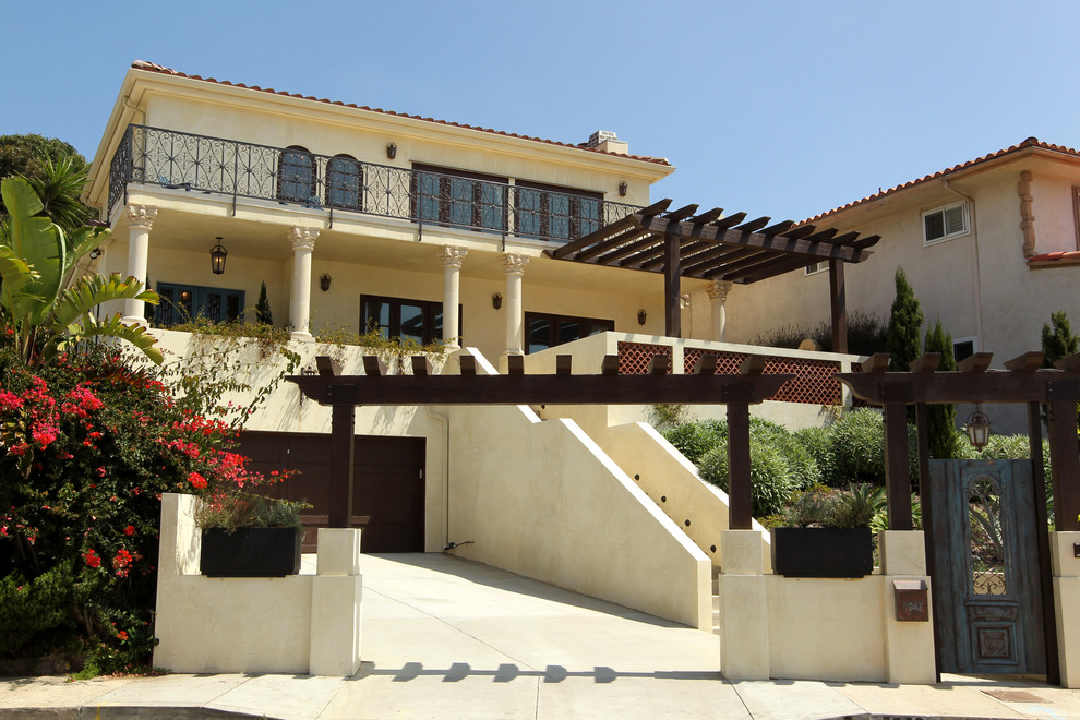 Esempio della villa grande beige mediterranea a due piani con rivestimento in stucco, tetto a padiglione e copertura in tegole