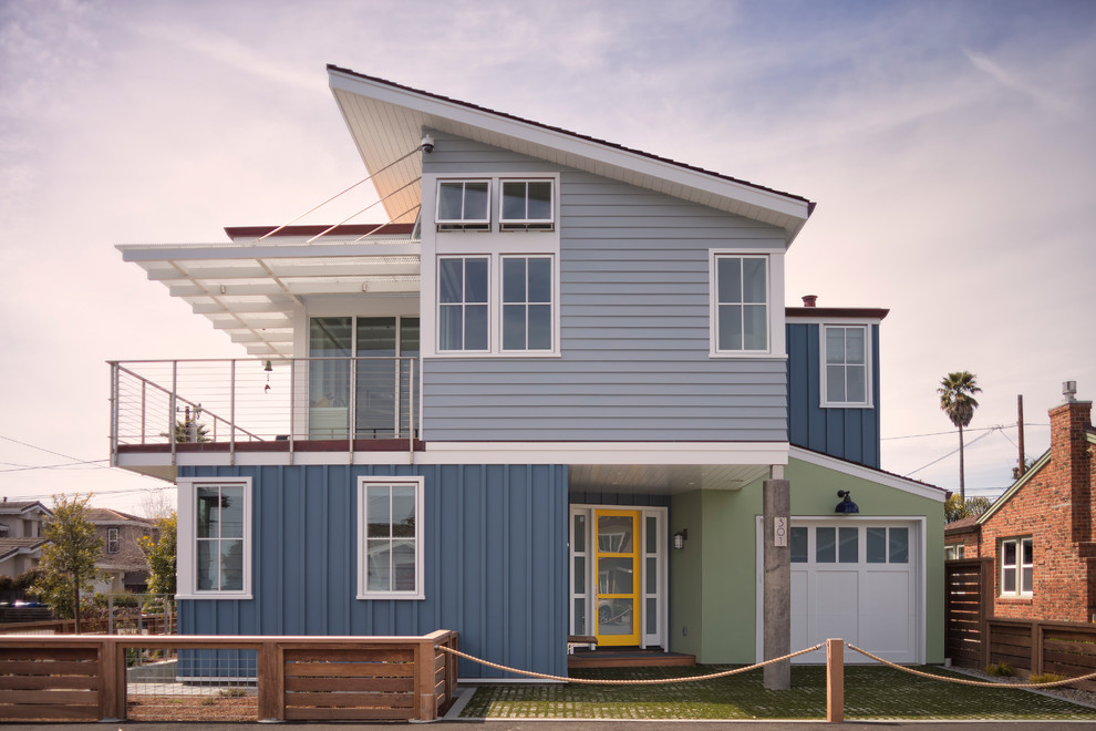На фото: маленький, двухэтажный, разноцветный частный загородный дом в морском стиле с комбинированной облицовкой, односкатной крышей и крышей из смешанных материалов для на участке и в саду