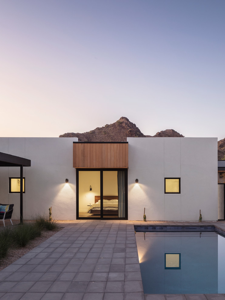 Cette image montre une façade de maison minimaliste en bois de plain-pied avec un toit à deux pans et un toit en métal.