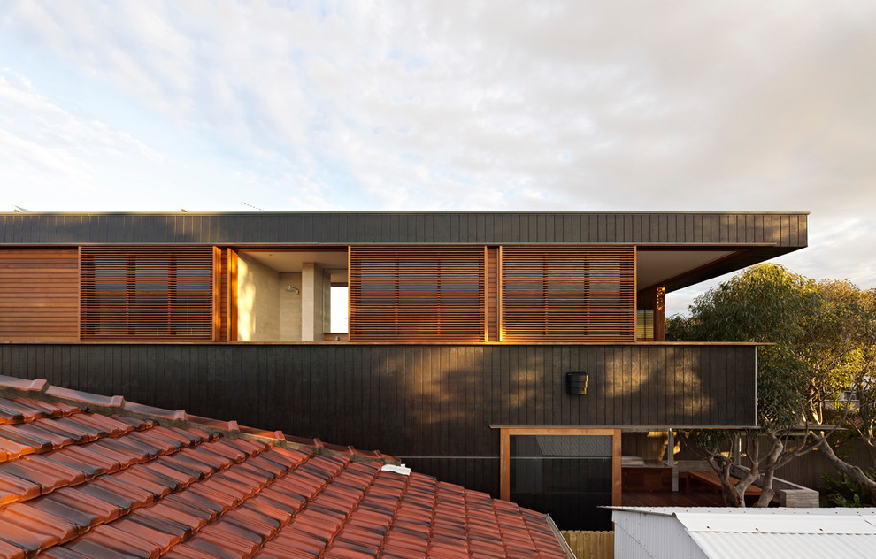 Imagen de fachada negra actual de tamaño medio de dos plantas con revestimiento de madera y tejado plano