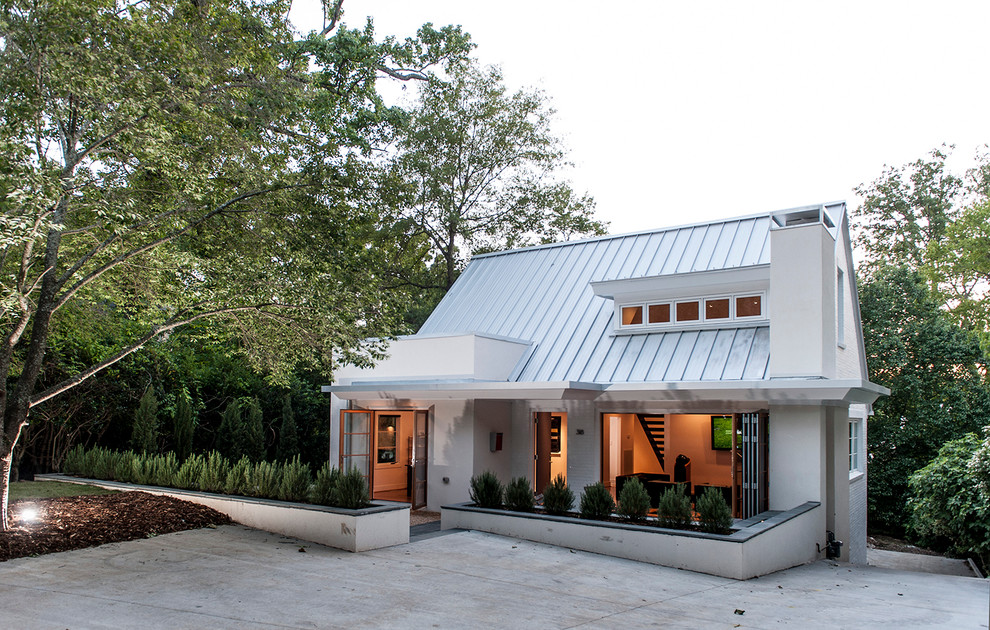 Ejemplo de fachada de casa blanca clásica renovada pequeña de dos plantas con tejado a dos aguas, revestimiento de estuco y tejado de metal