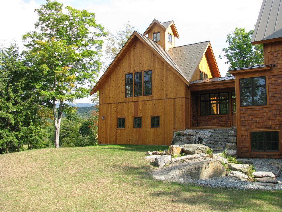 Cette photo montre une façade de maison montagne en bois à deux étages et plus avec un toit à deux pans et un toit en métal.