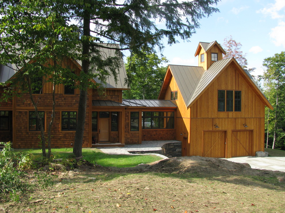 Immagine della villa rustica a tre piani con rivestimento in legno, tetto a capanna e copertura in metallo o lamiera