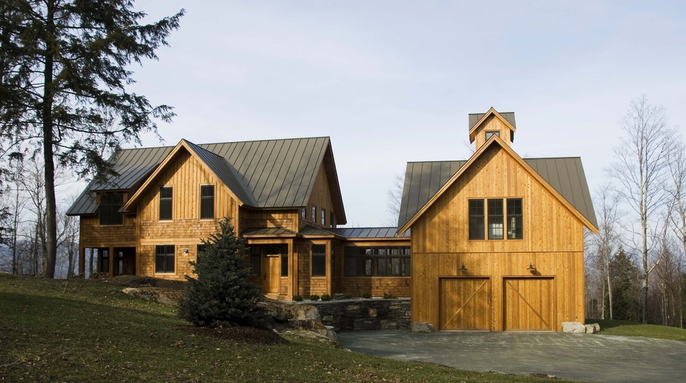 Foto della villa country a tre piani con rivestimento in legno, tetto a capanna e copertura in metallo o lamiera