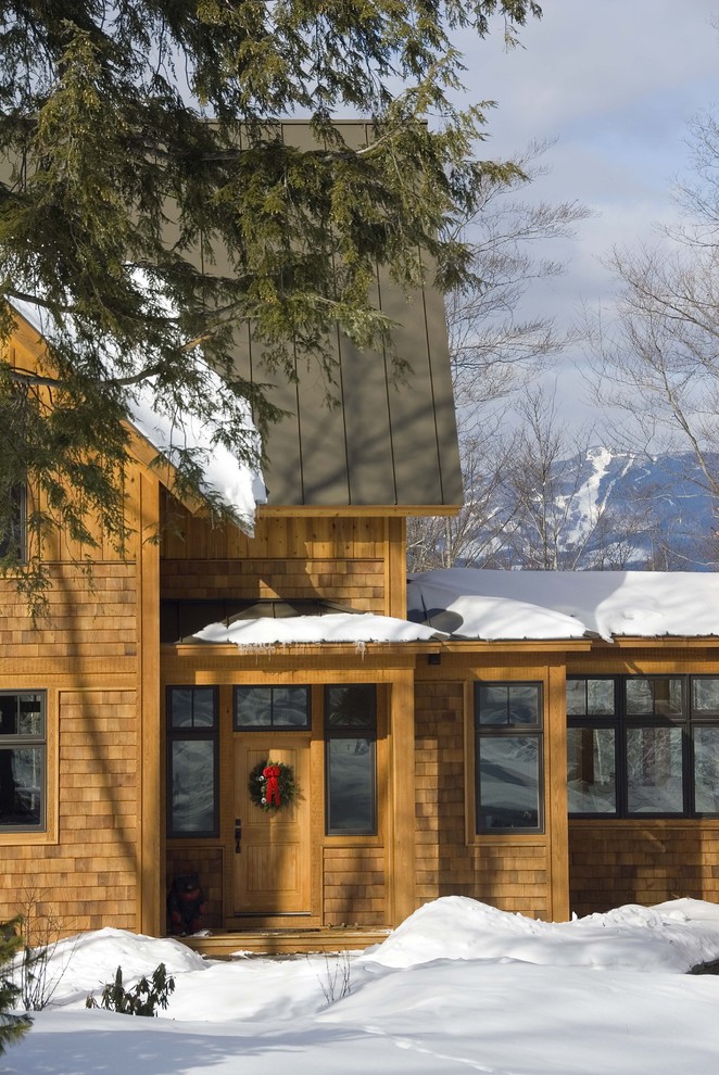 Cette photo montre une façade de maison montagne en bois à un étage avec un toit à deux pans et un toit en métal.