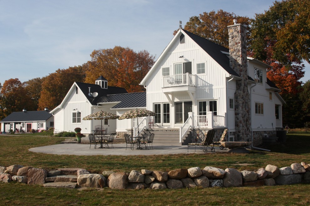 Diseño de fachada blanca de estilo de casa de campo de dos plantas con revestimiento de madera