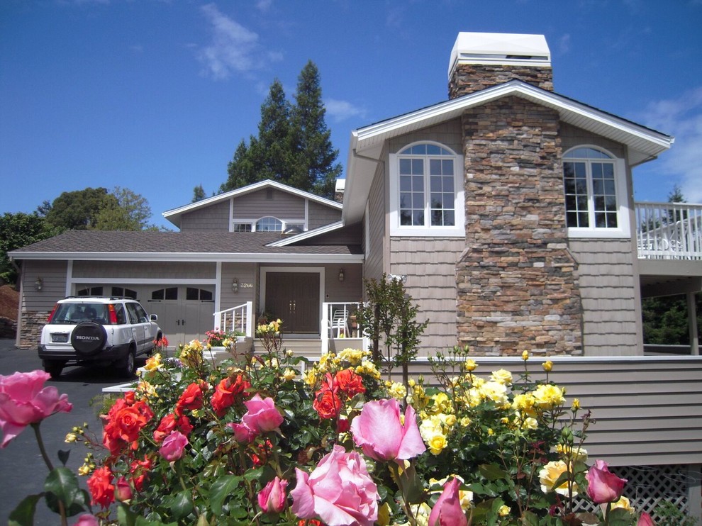 Modelo de fachada de casa beige clásica grande a niveles con revestimiento de madera, tejado a dos aguas y tejado de teja de madera