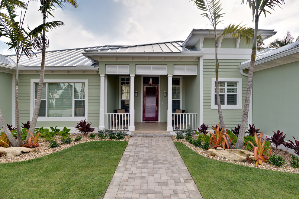 Example of a mid-sized island style green one-story exterior home design in Miami