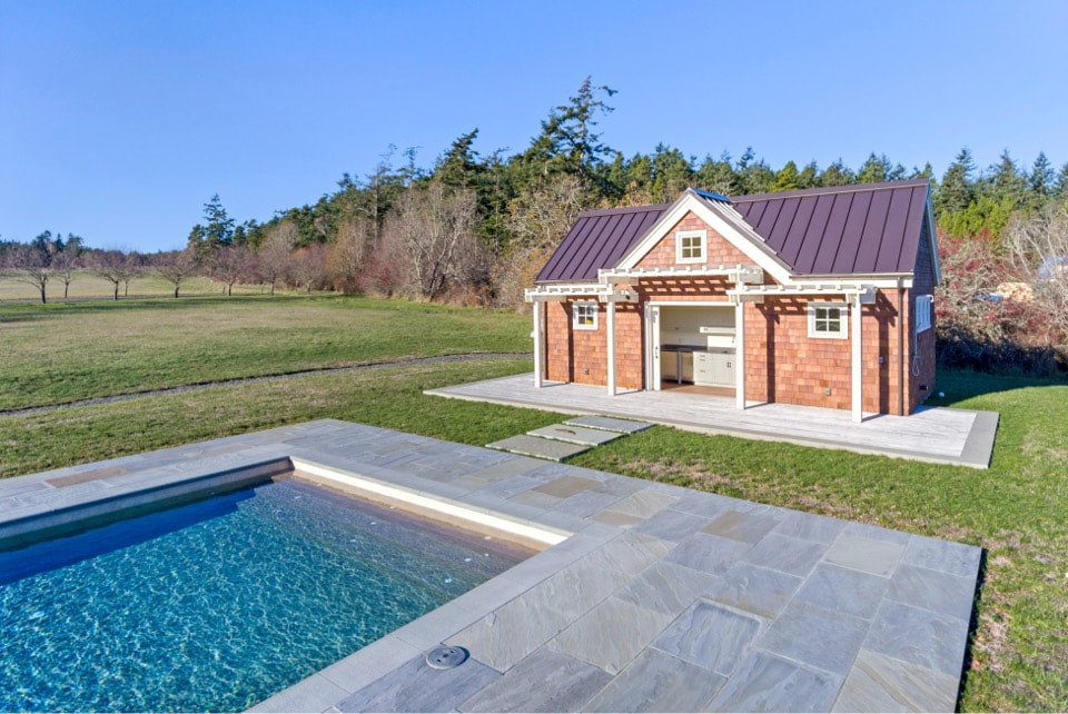 Immagine di una piscina costiera rettangolare di medie dimensioni e dietro casa con una dépendance a bordo piscina e pavimentazioni in pietra naturale