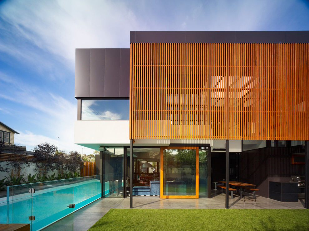 Cette image montre une façade de maison design avec un revêtement mixte.