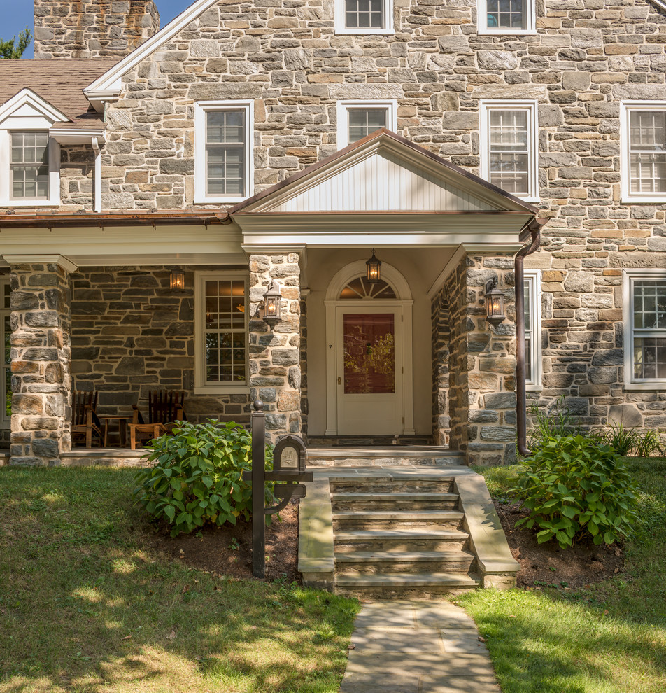 This is an example of a beige classic house exterior in Philadelphia with three floors, stone cladding and a pitched roof.