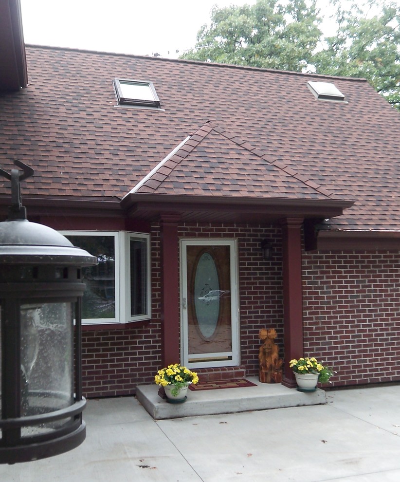 Esempio della facciata di una casa piccola rossa eclettica a un piano con rivestimento in mattoni e tetto a padiglione