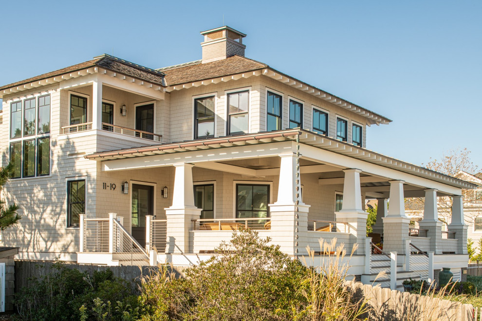 Esempio della villa grande beige stile marinaro a due piani con rivestimento in legno, tetto a padiglione, copertura a scandole, tetto marrone e con scandole