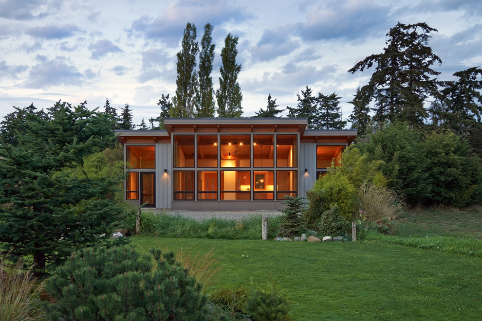 Cette image montre une façade de maison grise design de taille moyenne et de plain-pied avec un revêtement en vinyle et un toit plat.
