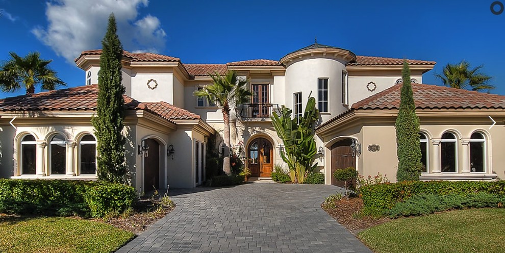 Medium sized and beige mediterranean two floor render detached house in Orlando with a hip roof and a tiled roof.