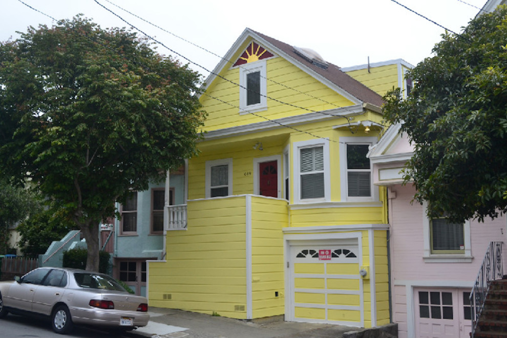 Immagine della facciata di una casa piccola gialla vittoriana a due piani con rivestimento in legno