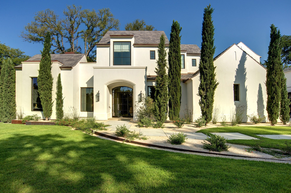Diseño de fachada blanca mediterránea de dos plantas con revestimiento de estuco y tejado a doble faldón