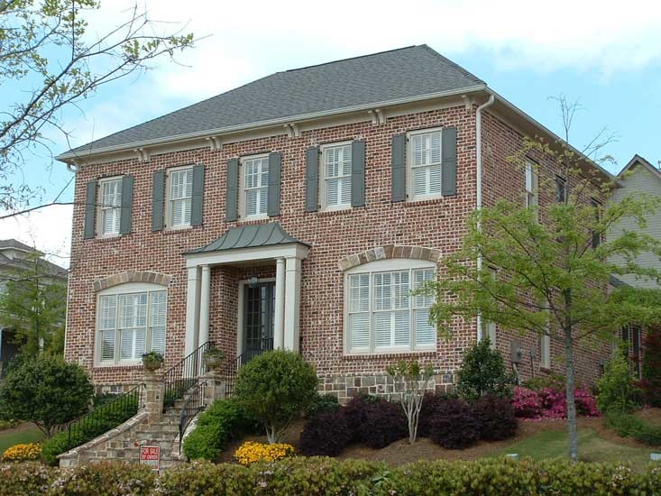 Aménagement d'une grande façade de maison multicolore classique en brique à un étage avec un toit à quatre pans et un toit en shingle.
