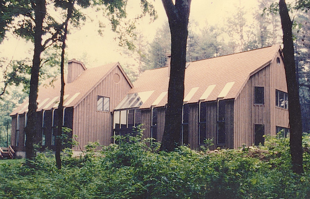 Cette photo montre une grande façade de maison marron rétro en bois à un étage avec un toit à deux pans.