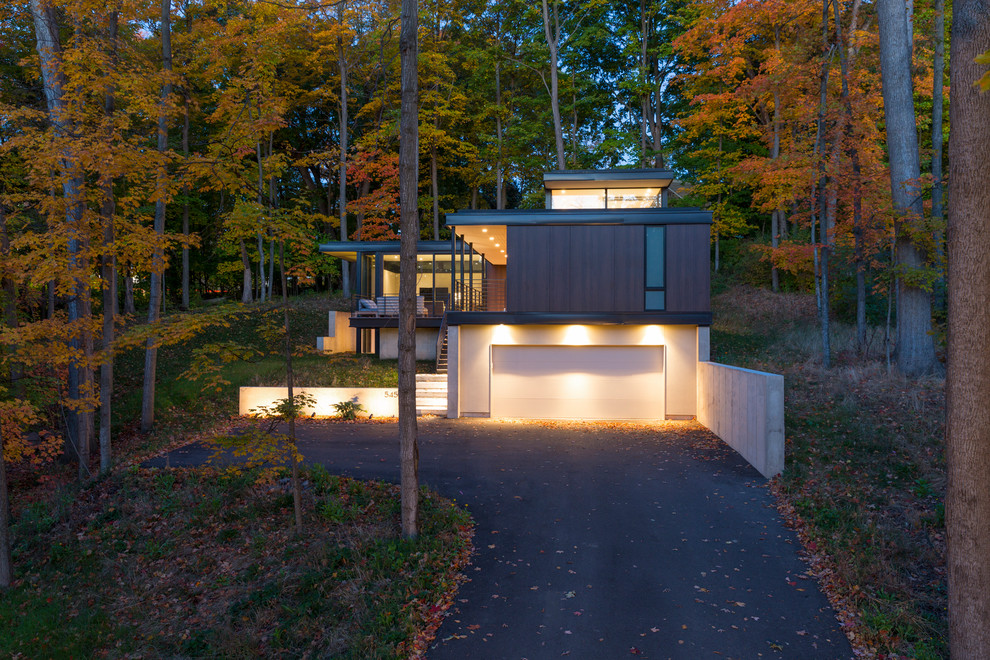 Cette image montre une façade de maison marron design à niveaux décalés avec un revêtement mixte et un toit plat.