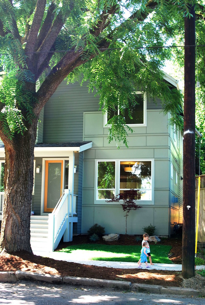 Ejemplo de fachada verde minimalista de tamaño medio de dos plantas con revestimiento de madera y tejado a dos aguas