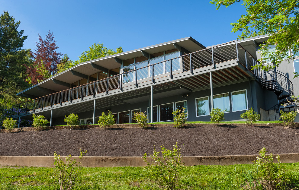 Idées déco pour une grande façade de maison grise rétro en bois à un étage avec un toit en métal et un toit noir.