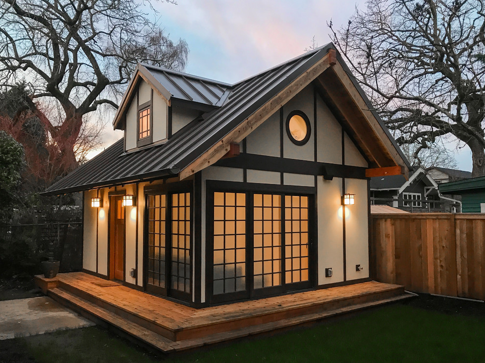 Cette photo montre une petite façade de maison beige asiatique en panneau de béton fibré de plain-pied avec un toit à deux pans et un toit en métal.