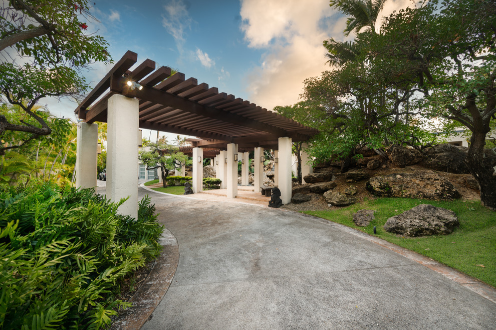 Esempio della villa ampia beige tropicale a un piano con rivestimento in stucco, tetto piano e copertura mista